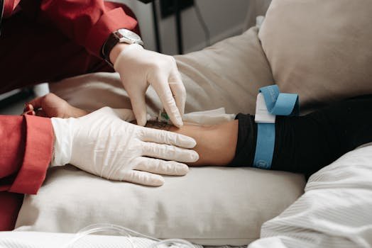 Medical professional in gloves inserting intravenous line into patient's arm in clinic setting.